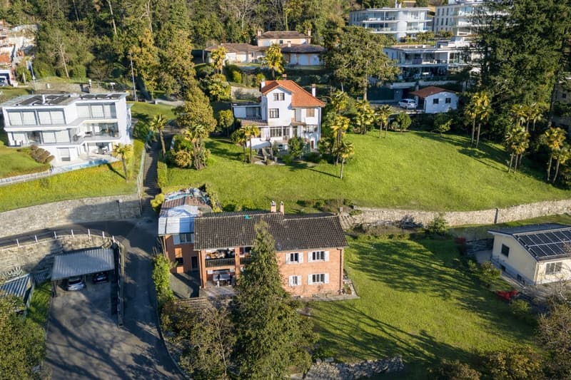 large green lawns, large house with solar panels, garage in front, trees, swimming pool