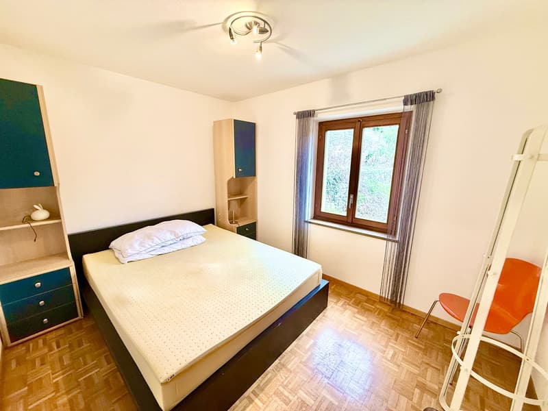 bedroom with bed, cabinets, window with curtains, ladder, and chair