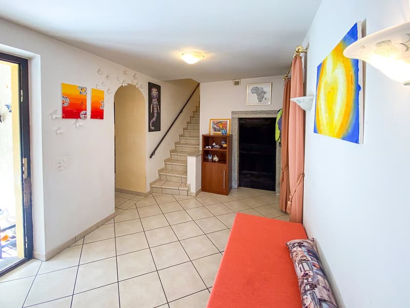 tiled floor, white walls, light fixtures, staircase, bench, fireplace, artworks on the wall