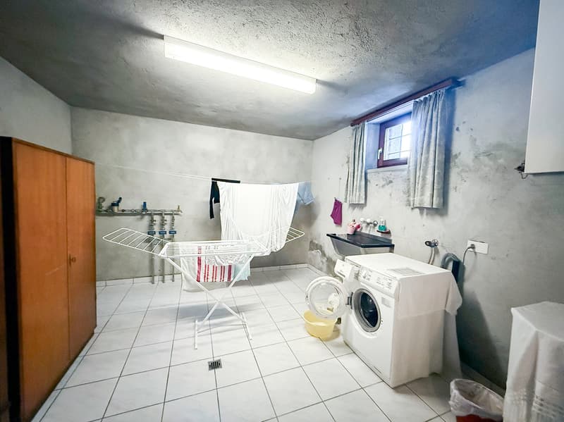 Tile flooring, white walls, washing machine, clothes drying rack, storage cabinet