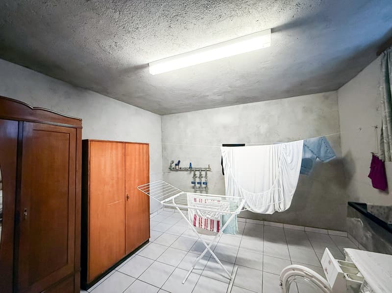 Tile flooring, white walls, wooden cabinets, clothes drying rack, washing machine