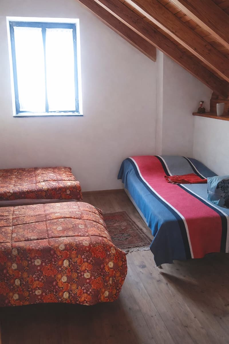 2 single beds, wooden floor, window, rug, wooden ceiling