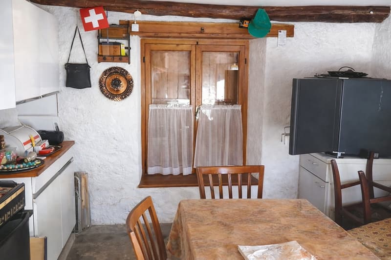 kitchen with dining area, wooden window, wooden chairs, table, white walls, wooden beams, Swiss flag