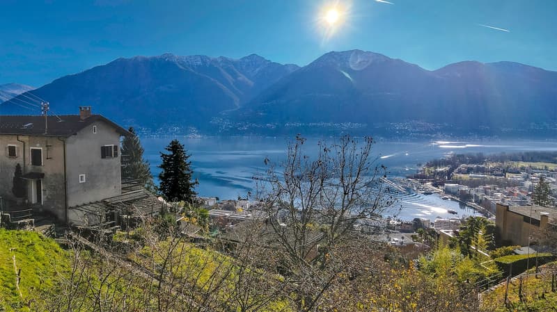 House on a hill with a view of the mountains and the lake