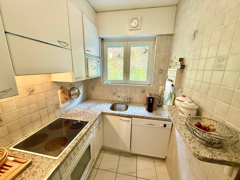 modern kitchen with granite countertops, electric stove, dishwasher, sink, microwave, cabinets, and a window