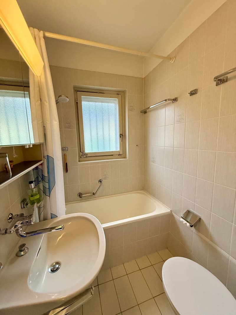 Bathroom with bathtub, sink, toilet, mirror, and window