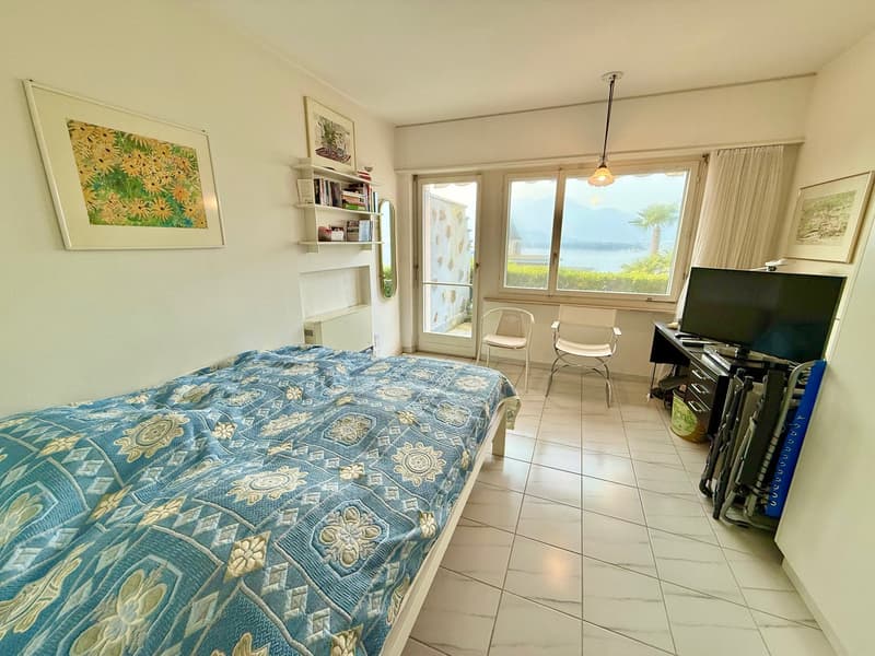 bedroom with bed, desk, TV, chairs, shelves, mirror, window with view