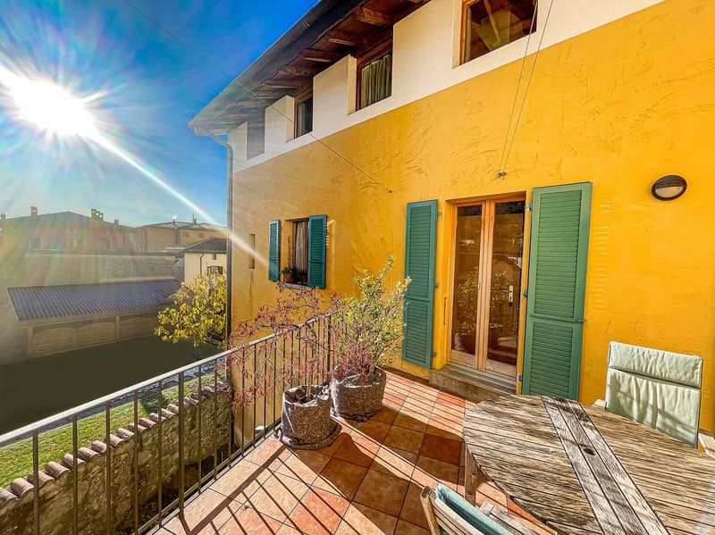 yellow exterior, green shutters, balcony with table and chairs, potted plants, sunny view