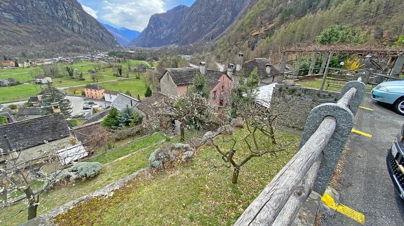 Mountain village, stone houses, green valley, mountain range, parking area, car