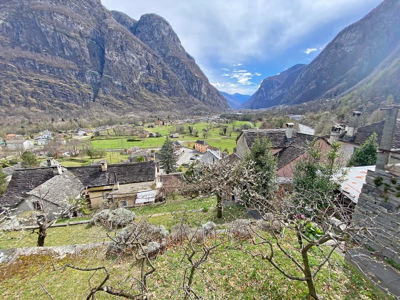 Mountain village with traditional stone houses, surrounded by green fields and mountains