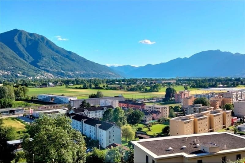 Aerial view of a town with buildings, mountains, and a lake in the distance