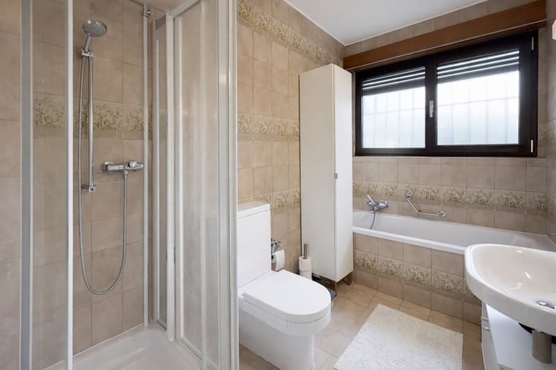 Bathroom with shower, bathtub, toilet, sink, and tiled walls and floor.