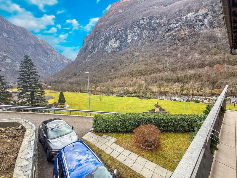 balcony, 2 parked cars, road, mountains, greenery, streetlight