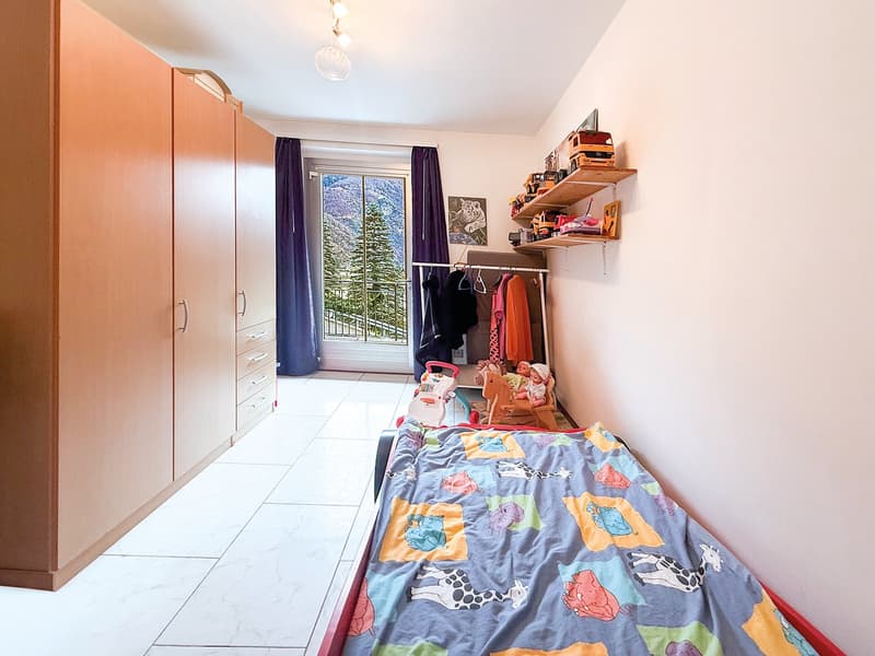 Small bedroom with single bed, closets, and balcony