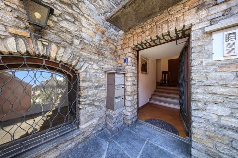 Stone wall entrance, open door, metal mailbox, steps leading to entrance