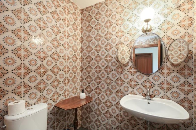 bathroom with sink, toilet, mirror, and tiled walls
