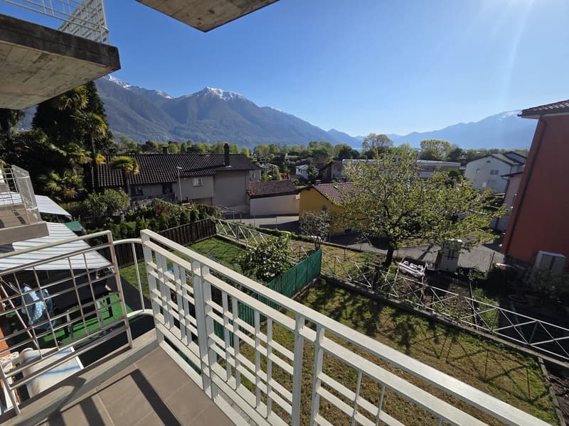 Balcony with metal railing, overlooking a garden and mountains