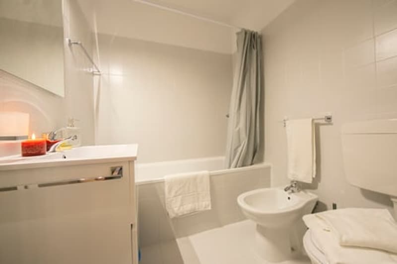 modern bathroom, white tiles, bidet, bathtub, sink, mirror, toilet, towels