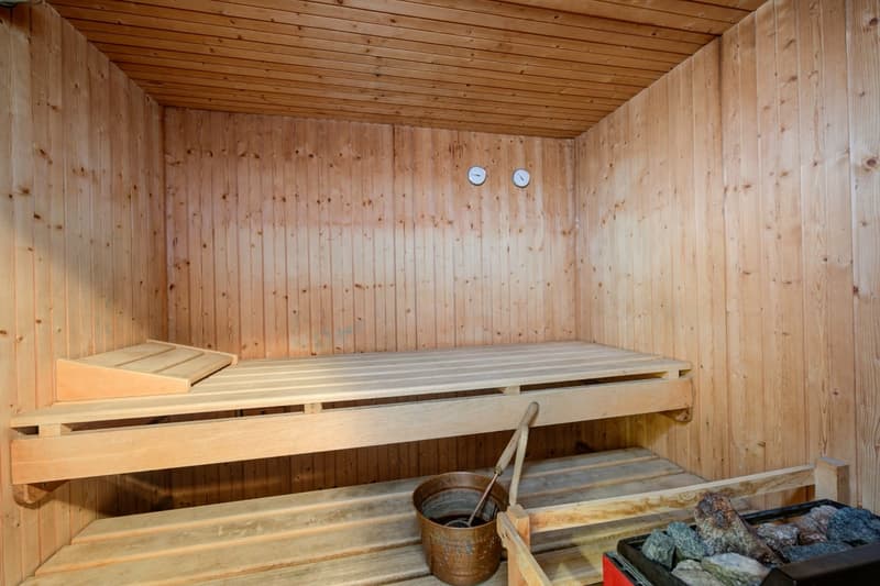 small sauna with wooden benches and small pail