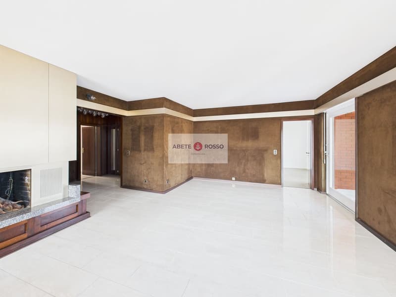 Large open living space with white tile flooring, brown accent walls, and a fireplace. The room has a modern and minimalist design.