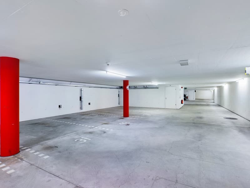 underground parking lot with two red pillars and parking spots