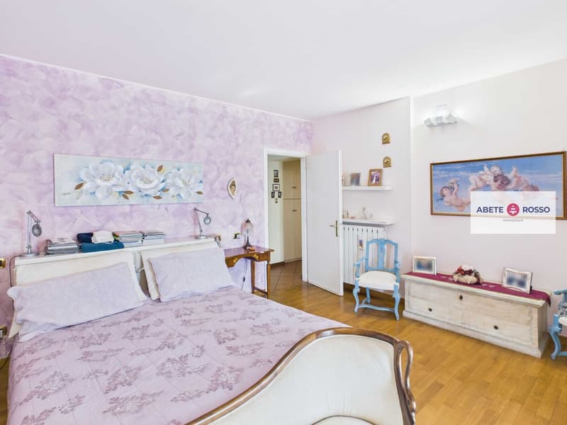 double bed with pillows, wooden floor, night lamps, table, wall paintings, desk, chair, heater