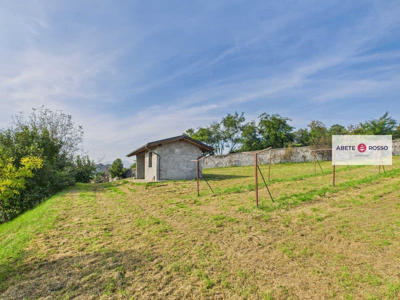 green field with a small house, stone wall, clear sky