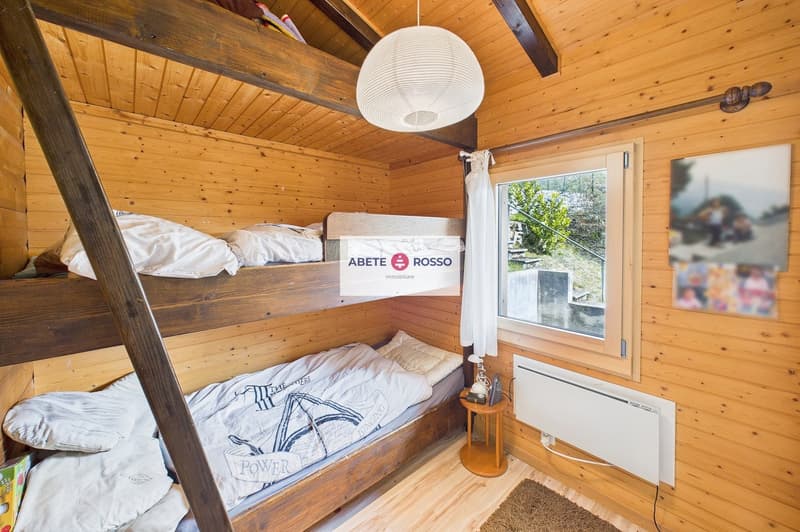 wooden walls, bunk beds, white bedding, window with white curtains, small table, radiator, rug