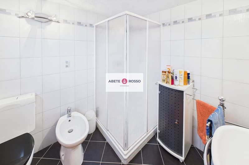 modern bathroom with white tiles, bidet, toilet, shower, sink, towel rack, toiletries