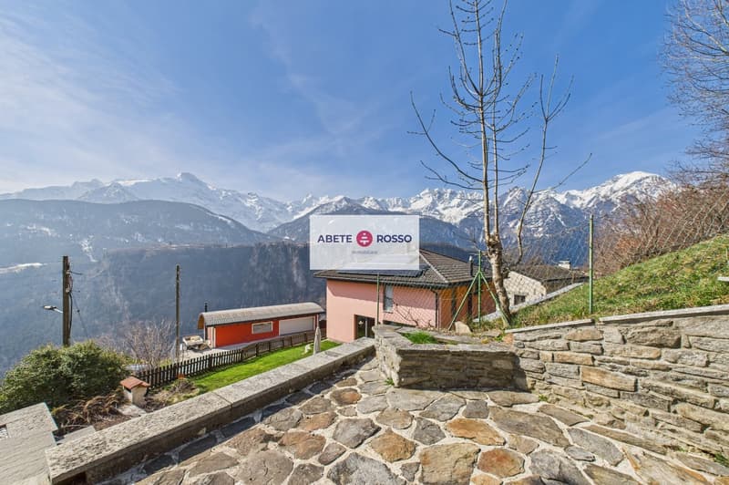 House with a view of the mountains, stone wall, solar panels on the roof, small red house