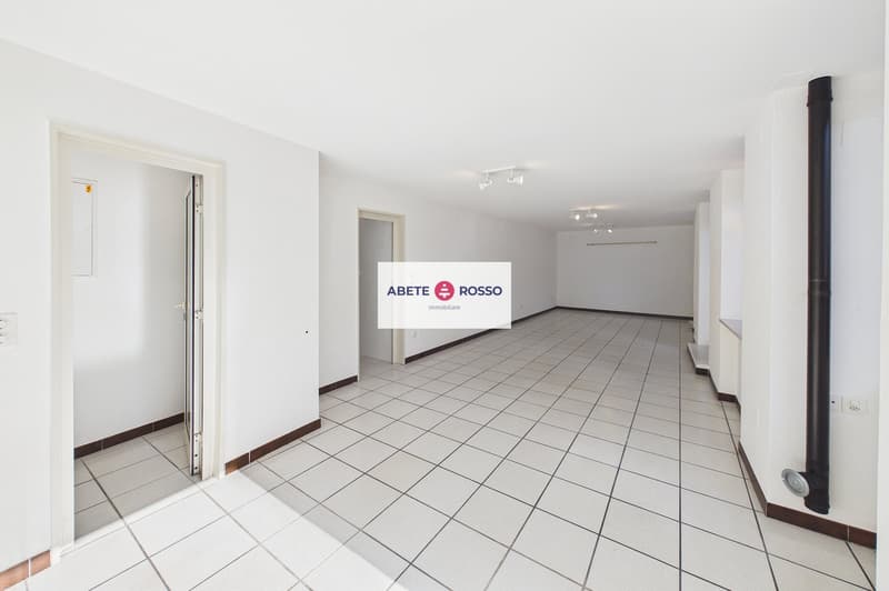 Empty room with white tiles, white walls, open door, ceiling lights