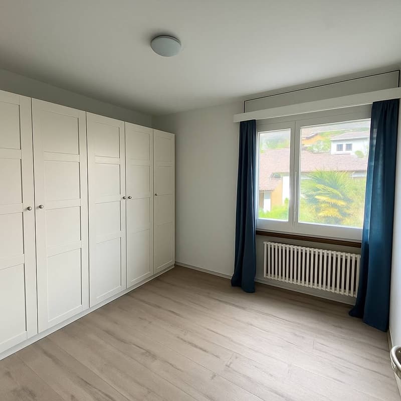 wooden floor, white wardrobes, large window with blue curtains, white radiator, central ceiling lamp