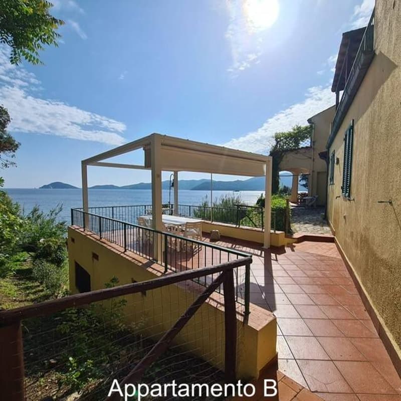 yellow house, sea view, balcony with pergola, tiled floor, table and chairs on balcony