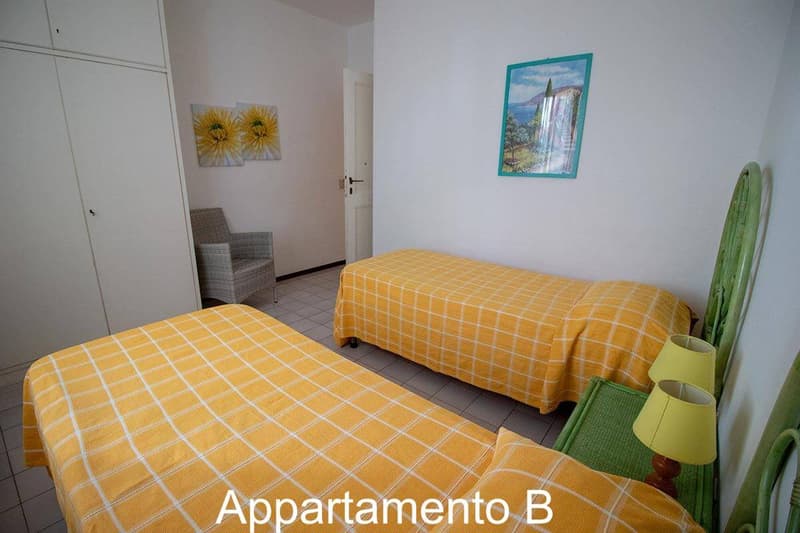 2 single beds, lamps, wall pictures, chair, wardrobe, tiled floor