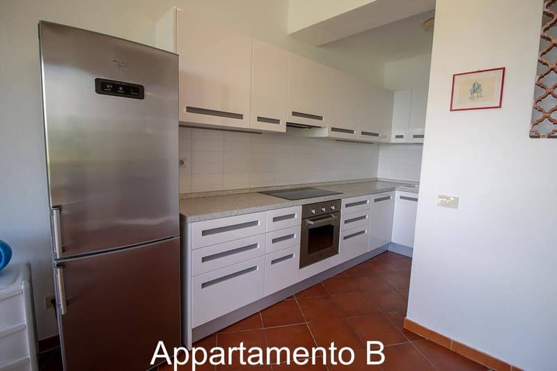 Modern kitchen with stainless steel refrigerator, gas stove, oven, tiled flooring, white cabinets, and appliances.