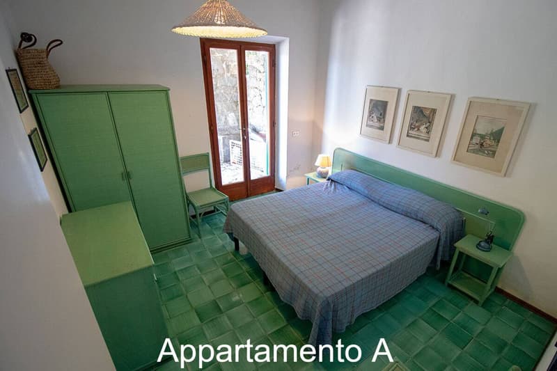 Bedroom with bed, green walls, tiled floor, door, chair, lamps, green furniture, pictures on wall