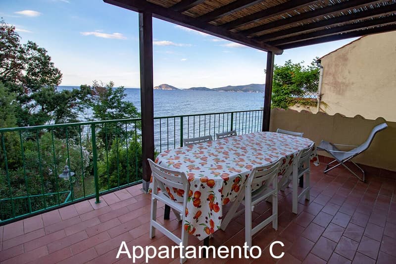 covered balcony, table and chairs, green railing, sea view