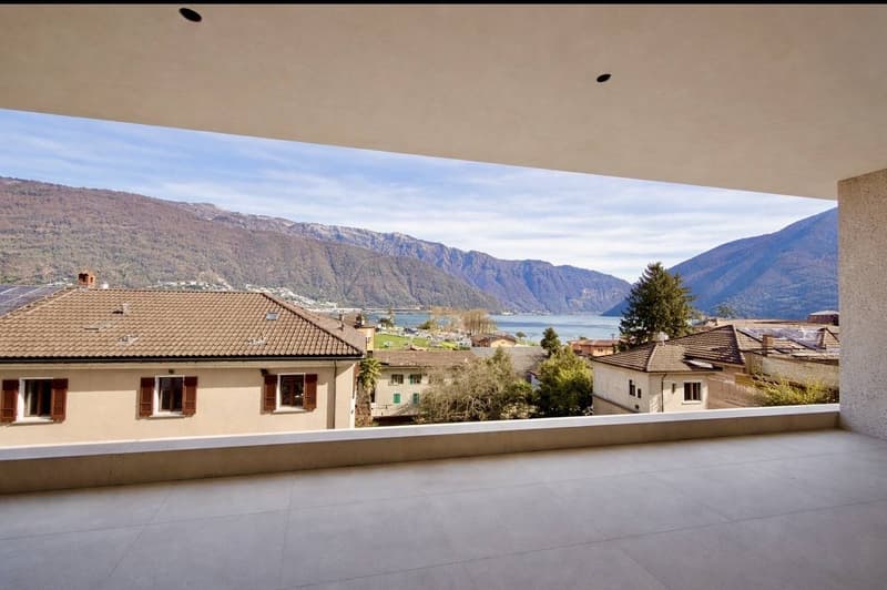 House with tiled roof, solar panels, large windows, balcony with tiled floor, view of mountains and lake