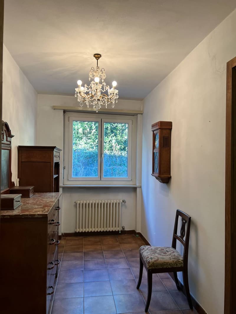 room with chandelier, wooden chair, wooden cabinet, wooden clock, window, radiator