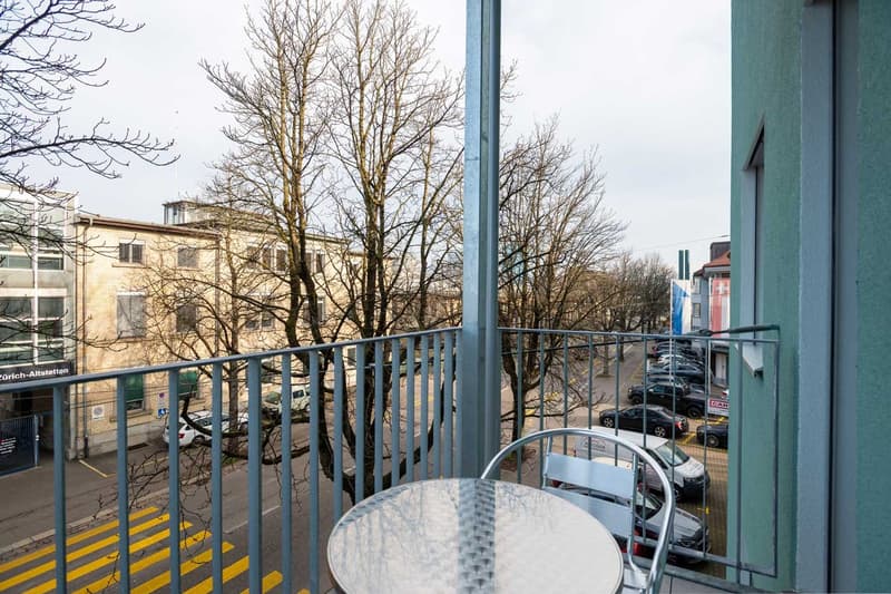Balcony with a view of bare trees and buildings, parking spaces visible below