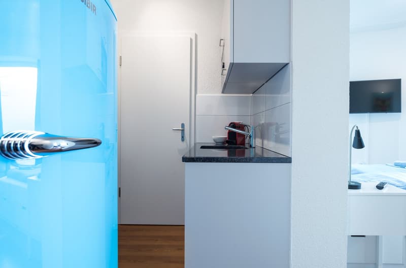 Modern kitchen with white cabinets, black granite countertop, and a dishwasher visible on the counter.