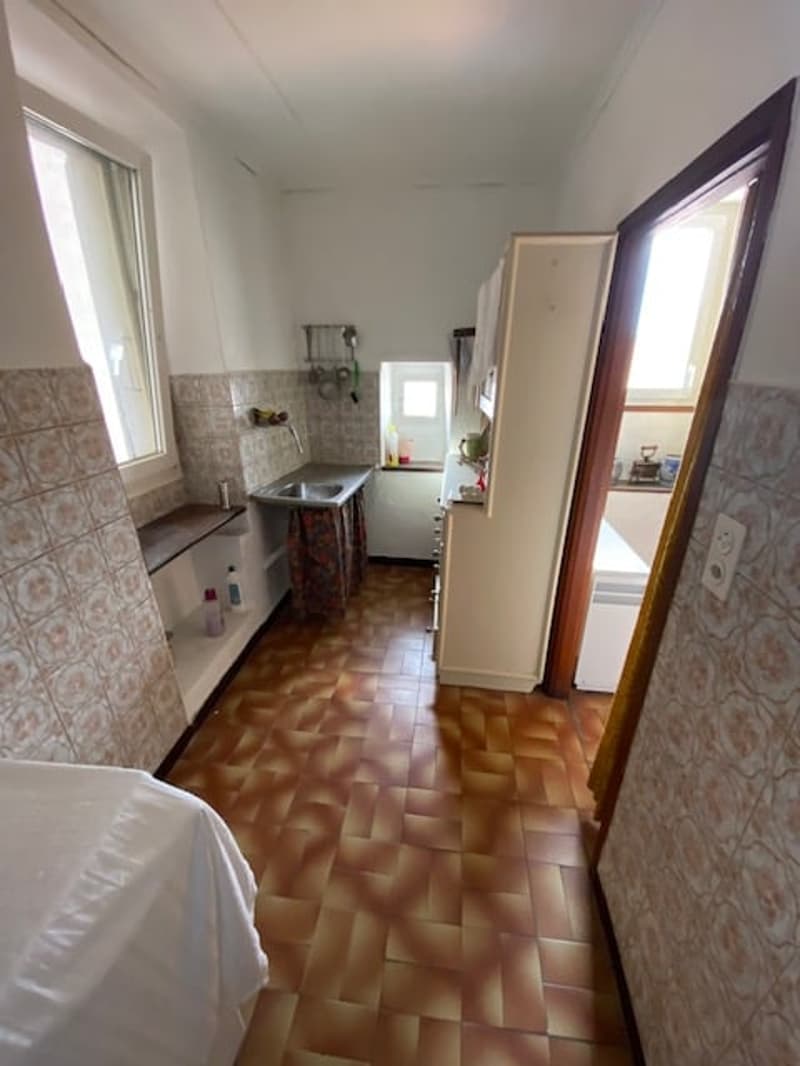 kitchenette with sink, tiled floor, white bed cover, small kitchen area with fridge, counter and window