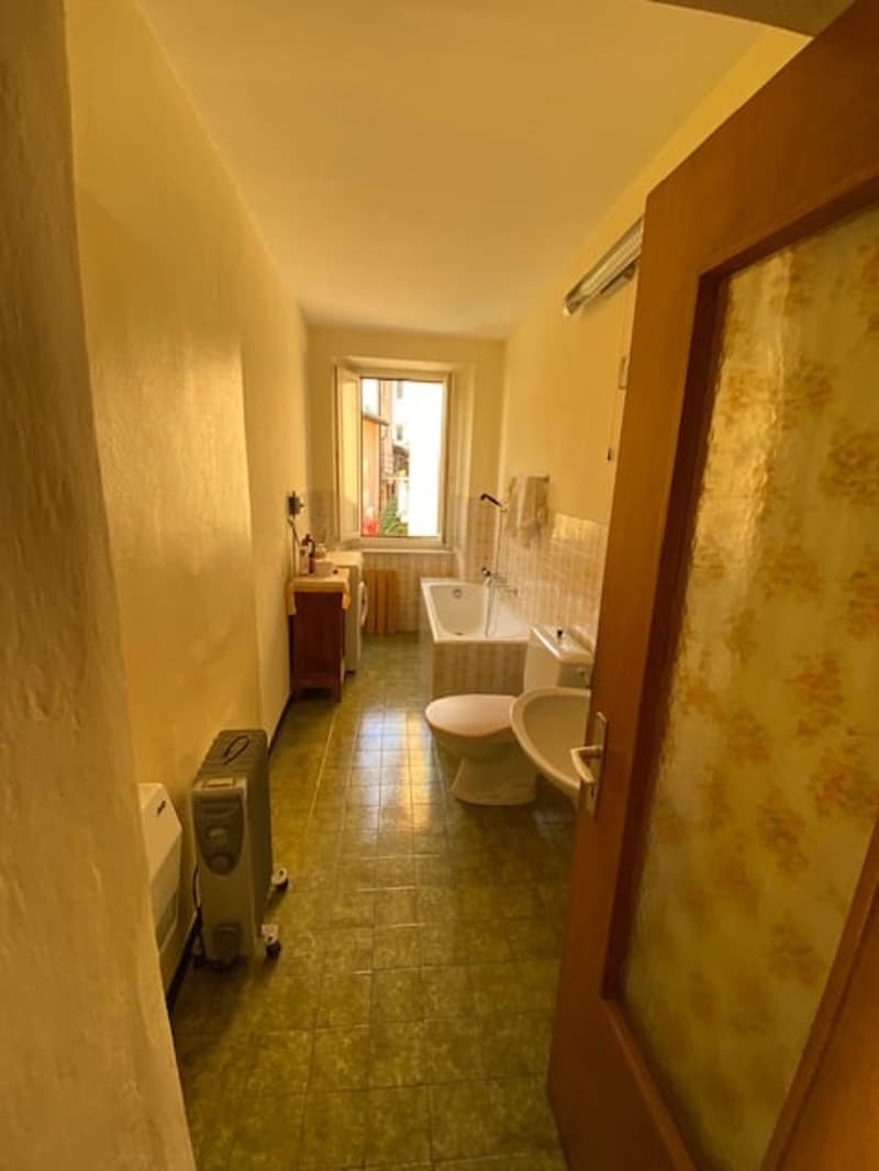 Bathroom with bathtub, toilet, sink, wooden cabinet, shower area, heater, window