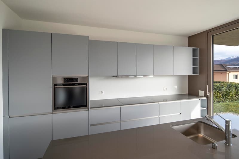 Modern kitchen with built-in appliances, gray cabinets, granite countertop, stainless steel sink, electric hob