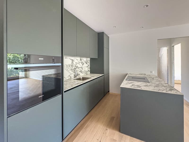 Open-plan kitchen with integrated Siemens dishwasher, stainless steel appliances, large marble island countertop, and gray cabinets with wooden floors.