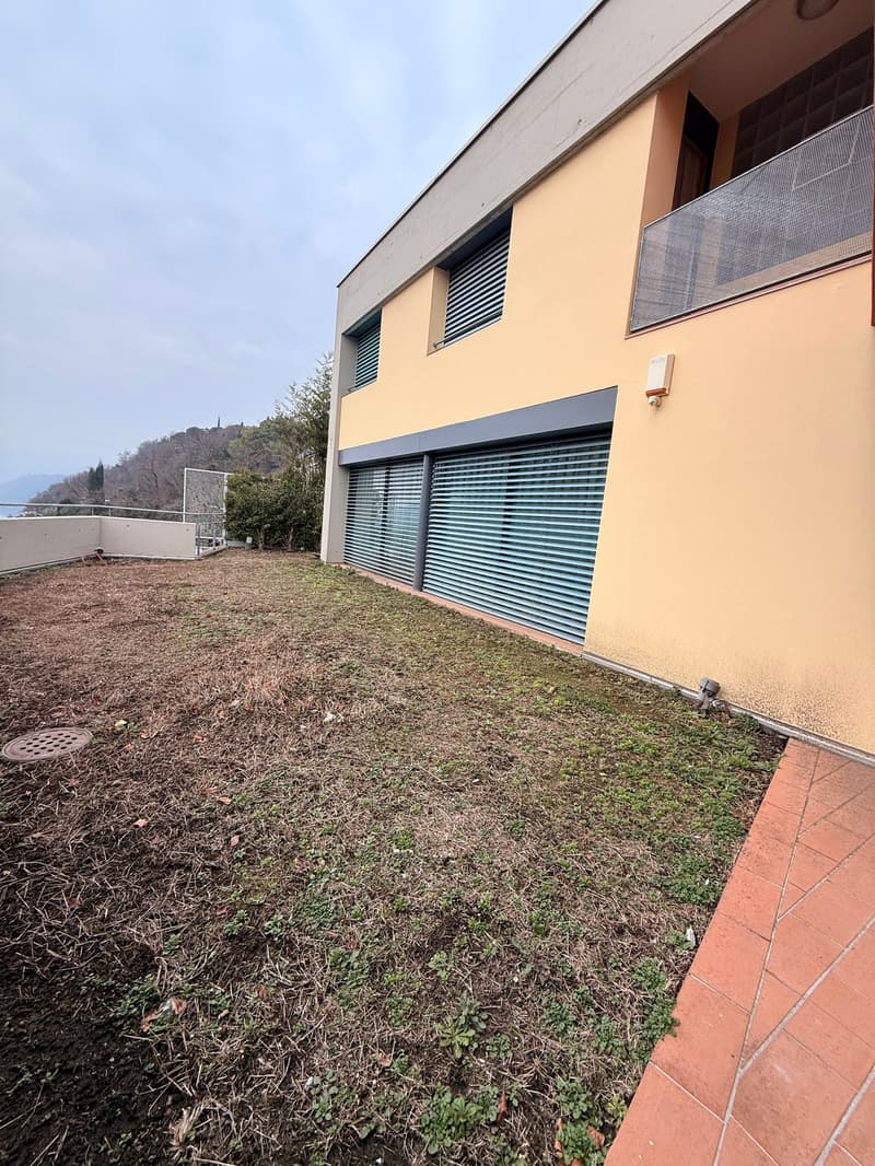 modern apartment with garage, balcony, driveway, lawn, small plants, and tile flooring