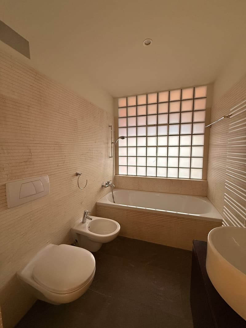 Rectangular bathtub, glass window, toilet, bidet, sink, tiled walls
