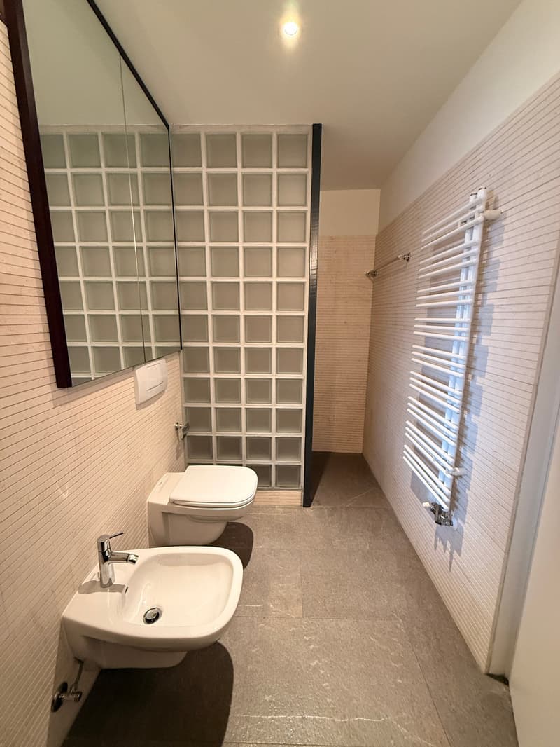 white tiled floor, white sink, white toilet, white shower with glass walls