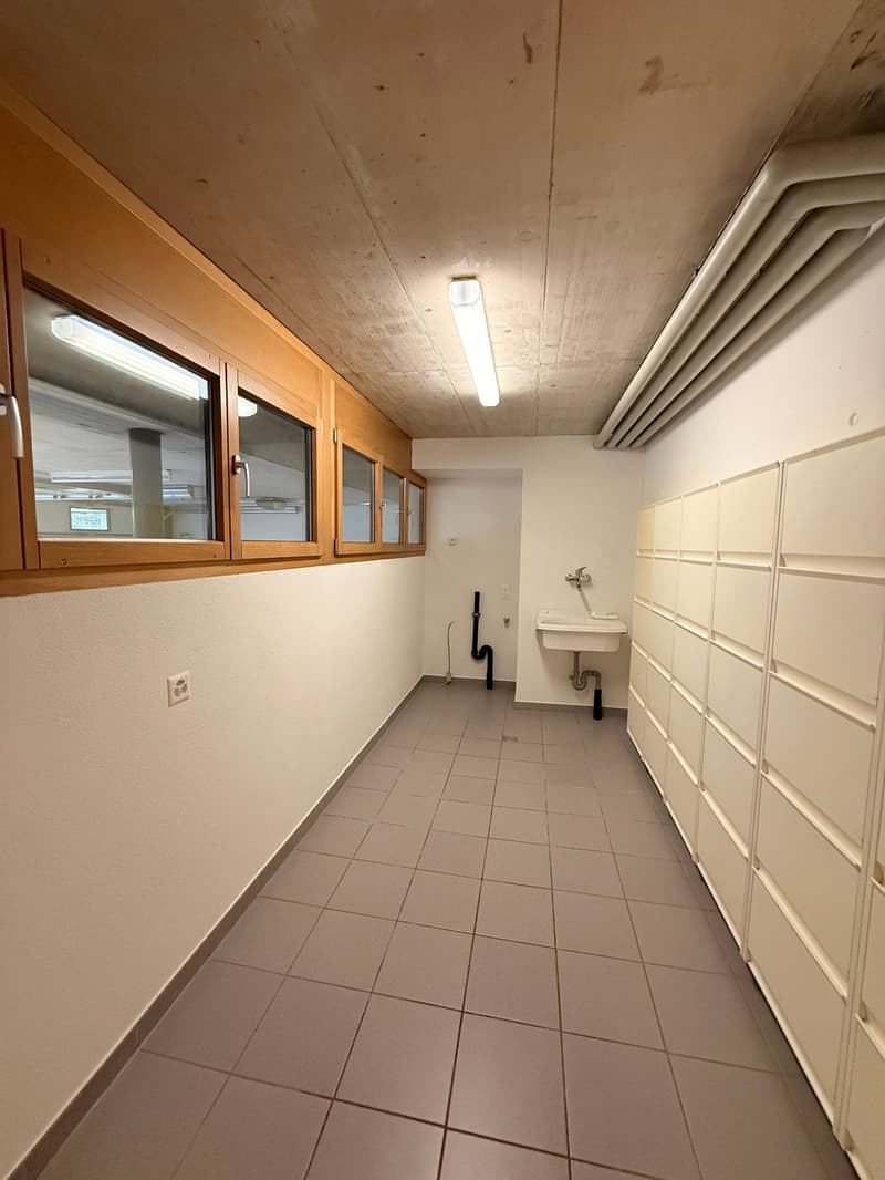 tiled floor, wooden cabinets, windows, ceiling light, white sink, plumbing pipes, power outlet