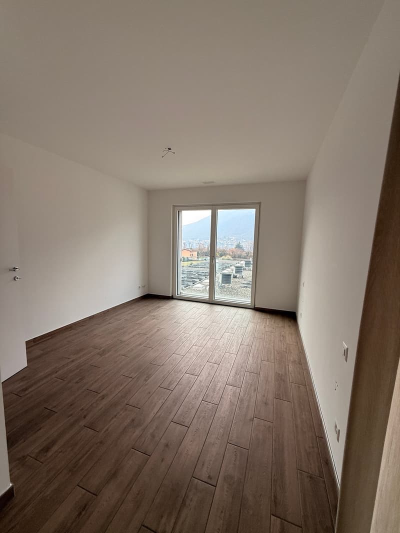 empty room with sliding glass door to balcony, wooden floor, white walls, power outlets